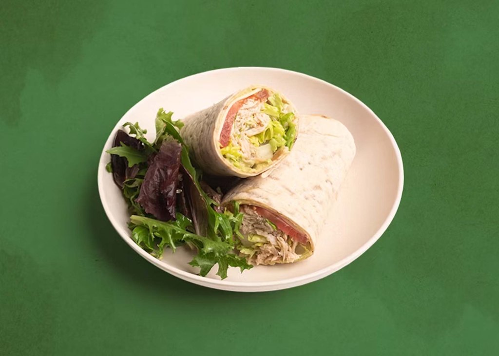 Turkey wrap, sliced in two and stacked askew, with small side of salad greens